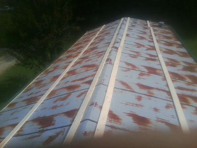 Rusted metal roof panels with new wood purlins before replacement — Storm Damage Roof Repair in Blue Mound by Roofing Brothers