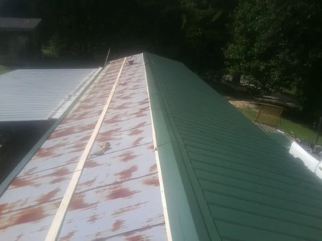 Old rusted panels beside newly installed green metal roofing — Wind Damage Roof Repair by Roofing Brothers in Blue Mound