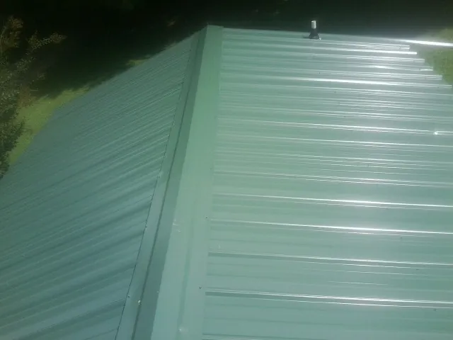 New green metal panels meeting at the ridge of a roof — Flat Roof Repair work by our crew in Blue Mound