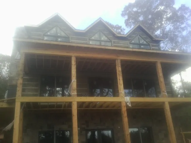 Dormers and porch framing on a large log home under construction — Roof Coating work by our crew in Blue Mound