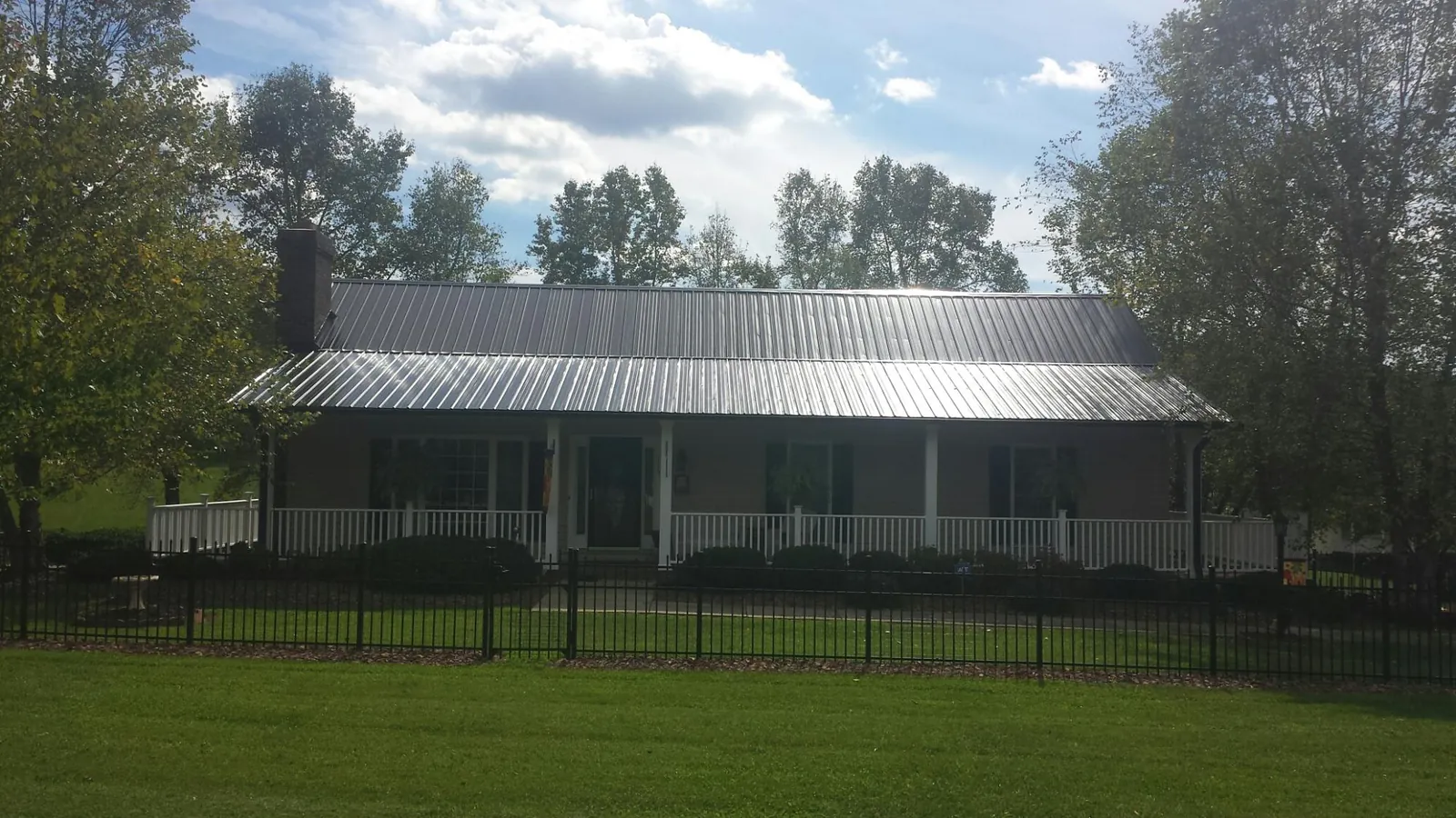 Gray metal roof on a brick ranch with a full width front porch — Gutter Guard Installation work by our crew in Blue Mound