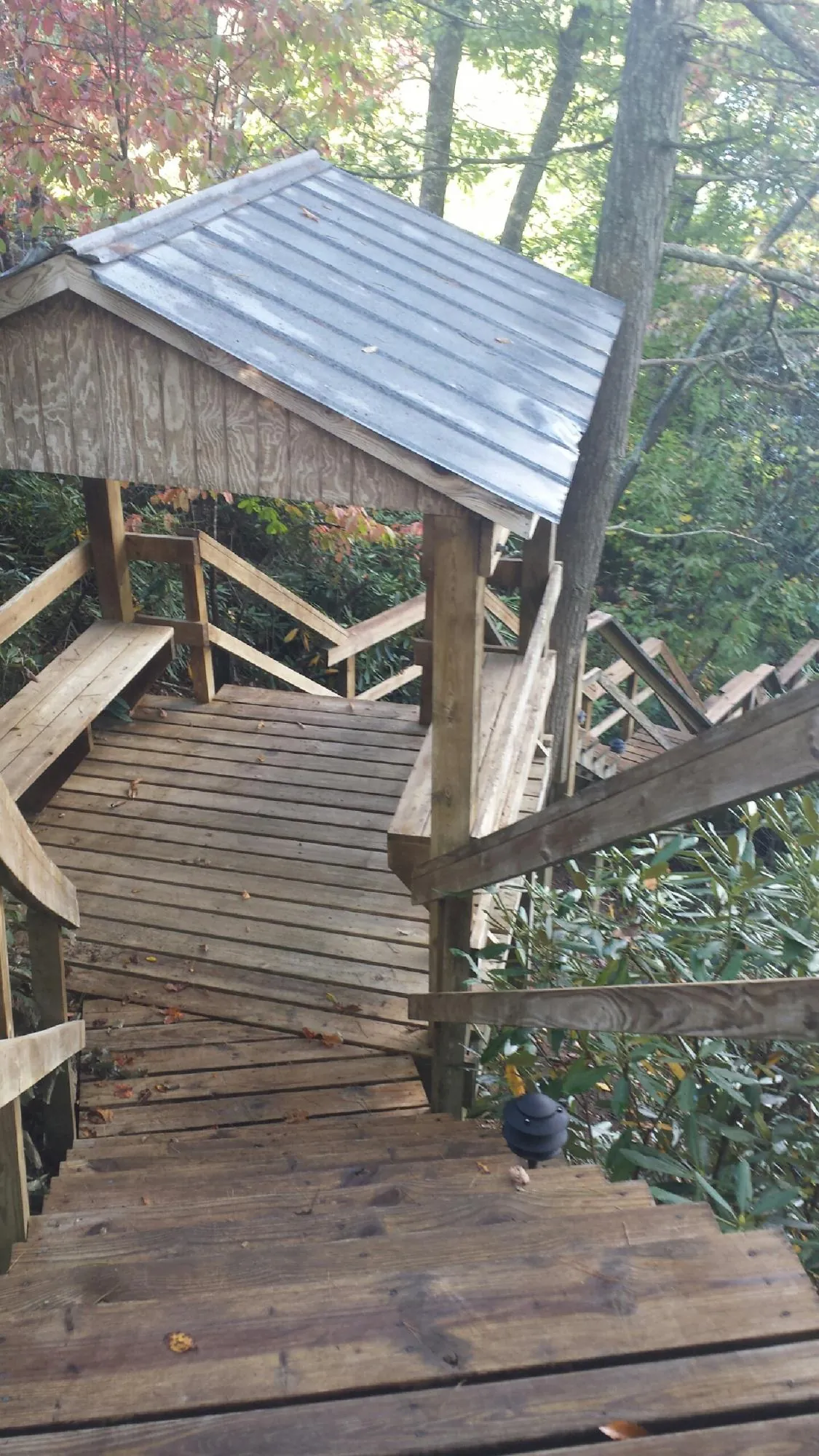 Metal roofed shelter over wooden steps on a wooded walkway — Skylight Repair & Installation work by our crew in Blue Mound