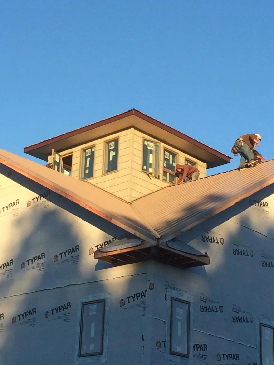 Roofers working around a rooftop cupola on a new metal roof at sunset — Roof Waterproofing in Blue Mound by Roofing Brothers